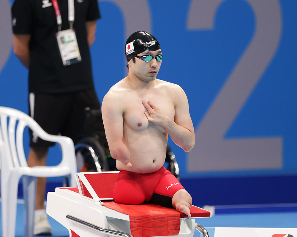 写真：飛び込み台の上で、左手を胸に当てプールを見据えるパラスイマー・鈴木孝幸選手