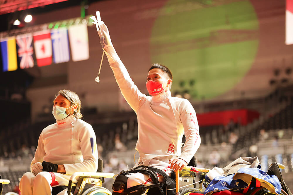 写真：車いすフェンシング日本代表の藤田道宣選手が競技会場で右手を高々と挙げている様子