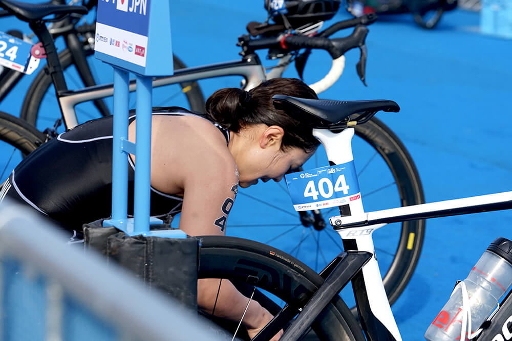 写真：自転車のわきでかがんでいるパラトライアスロン谷_真海選手