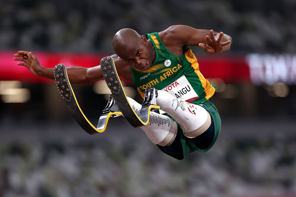 写真：男子走幅跳T63で金メダルを獲得した南アフリカのヌタンド・マーラング選手の、頭と義足のブレードがくっつきそうになるくらい両足高く跳躍を決めるシーン
