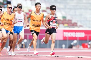 写真：伴走者とともに競技場のトラックを走る全盲のランナー唐澤剣也選手