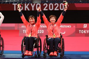 写真：：パラバドミントンダブルスでも金メダルを獲得した里見紗李奈選手とペアを組んでいる山崎悠麻選手がメダルをかけ万歳し喜んでいるシーン