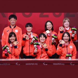 サムネイル画像：銅メダルとメダリストに送られる花のブーケを手に笑顔のゴールボール女子チームと市川監督