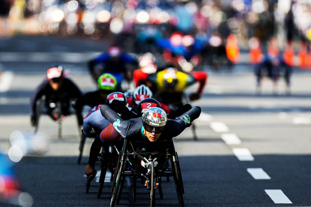 写真：第40回記念大分国際車いすマラソン・車道のコースを大勢の選手を従え先頭を走るマルセル・フグ選手