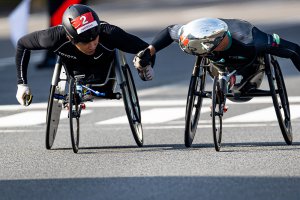 写真：第40回記念大分国際車いすマラソン・車道のコース上で挨拶するマルセル・フグ選手と鈴木朋樹選手