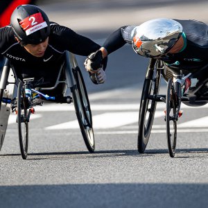 サムネイル写真：第40回記念大分国際車いすマラソン・車道のコース上で挨拶するマルセル・フグ選手と鈴木朋樹選手