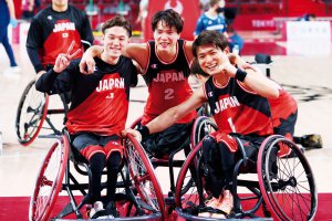 写真：コート上、喜びの笑顔で古澤拓也選手と豊島英選手の肩を抱く車いすバスケットボール鳥海連志選手