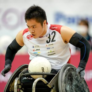サムネイル写真：写真：ボールを腿の上にのせ車いすを移動させる車いすラグビー橋本勝也選手
