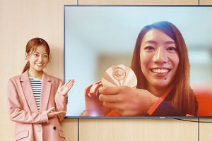 写真：スポーツキャスター・中川絵美里と大きな画面に映る、メダルを持った倉橋香衣選手（車いすラグビー）