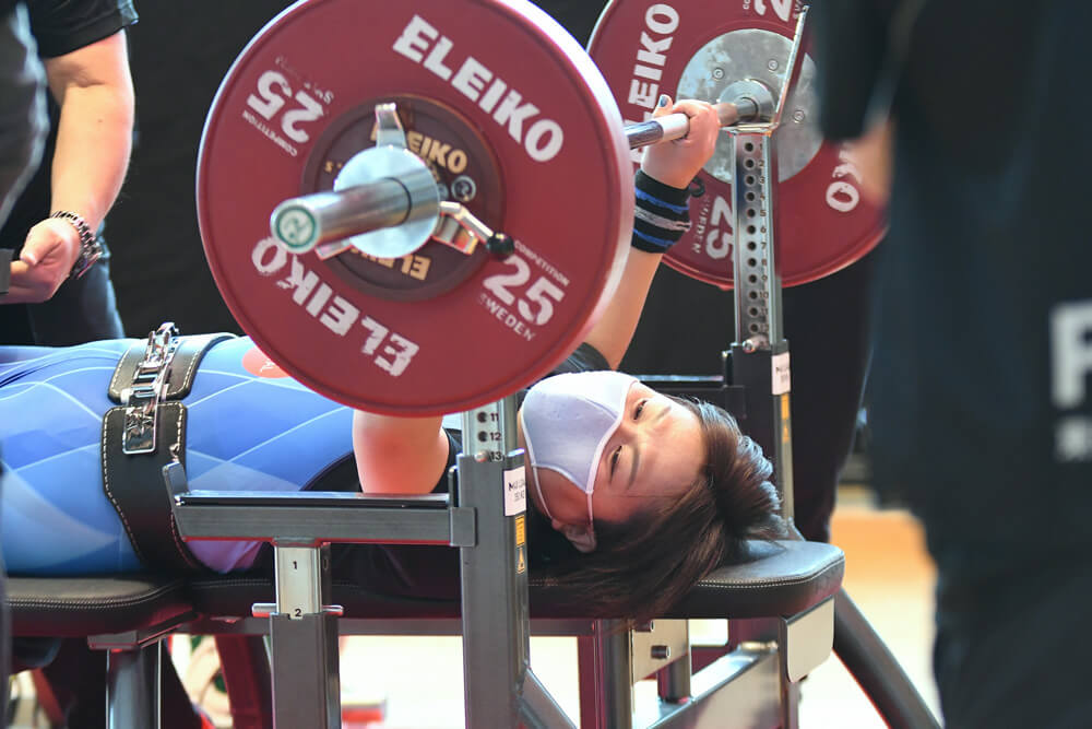 写真：女子79㎏級の坂元智香選手。マスクをしバーベルを持ち上げ練習に励む様子