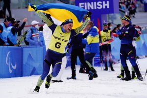 写真：最終日(3/13)のクロスカントリースキーオープンリレーで優勝し、 歓喜のウクライナチーム。ウクライナの旗を掲げて走る様子