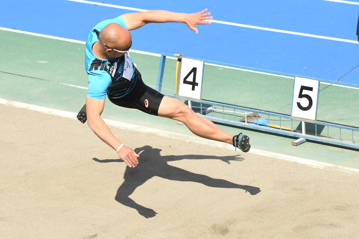 写真：走り幅跳びをする義足の選手。4～5m付近の空中を飛んでいる姿