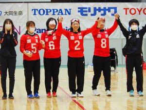 写真：2021年12月のジャパンパラで、赤いユニフォームを着たゴールボール選手4人が手をつないで笑顔を見せる様子。中央が浦田理恵選手