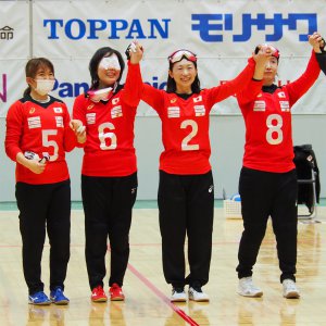 サムネイル用写真：写真：2021年12月のジャパンパラで、赤いユニフォームを着たゴールボール選手4人が手をつないで笑顔を見せる様子。中央が浦田理恵選手